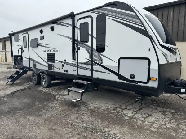 Large camper with multiple windows and steps.