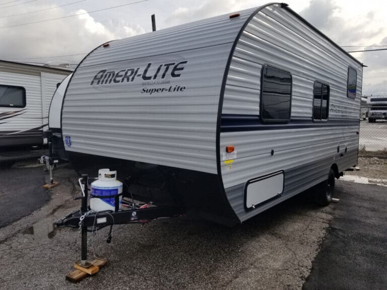 Silver travel trailer under cloudy sky.